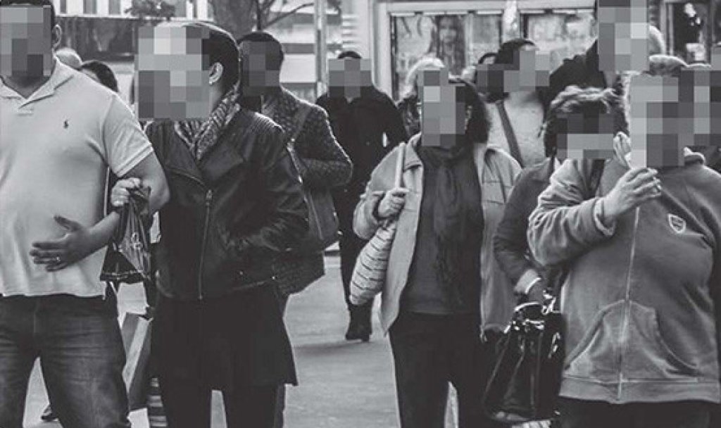 Group of people on a high street with faces redacted.