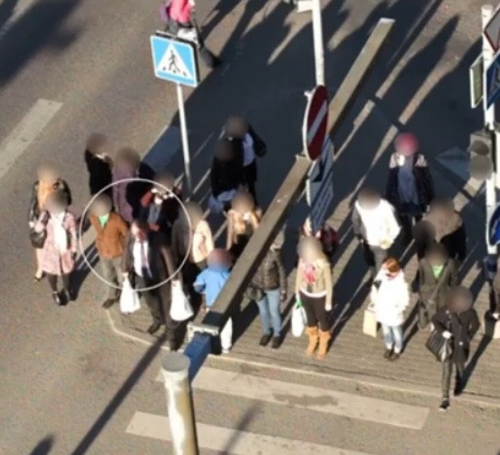 Image of people at a pedestrian crossing with their faces redacted.