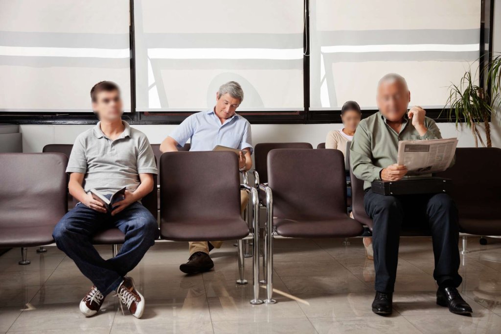 People sat in a waiting room – all but one face is redacted.