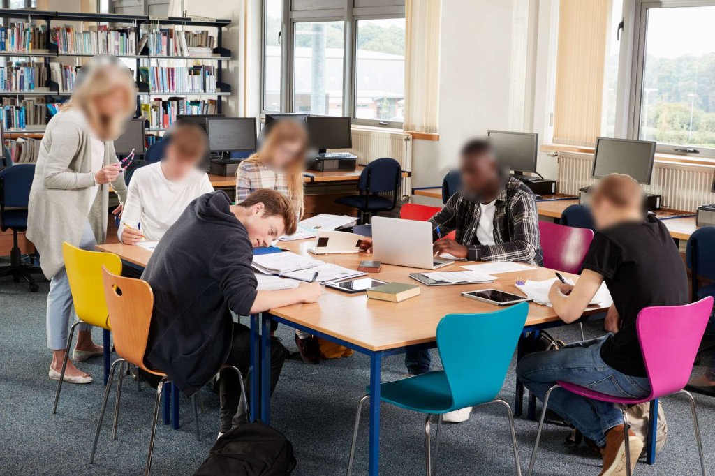 Students in a study room with faces redacted except for one.