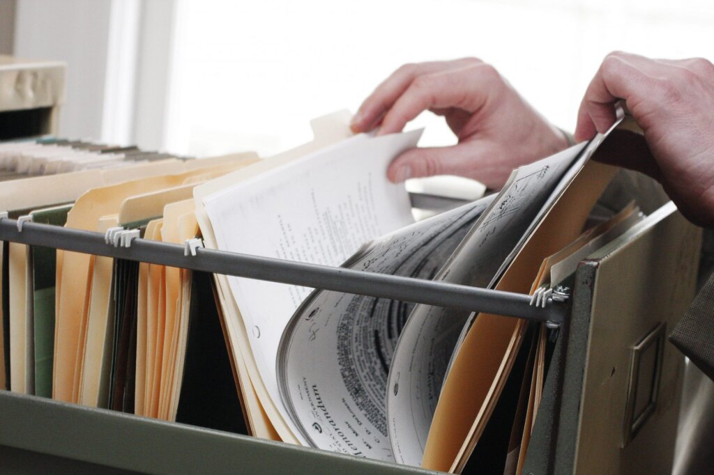 Hands looking through paper files.
