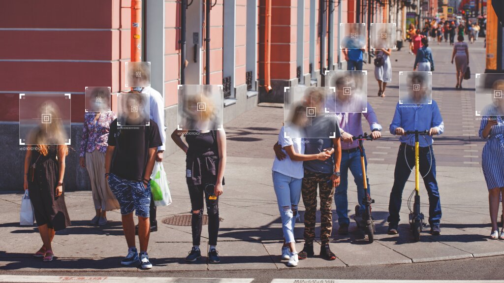 A group of people on a street with blurred white boxes depicting where their heads are.