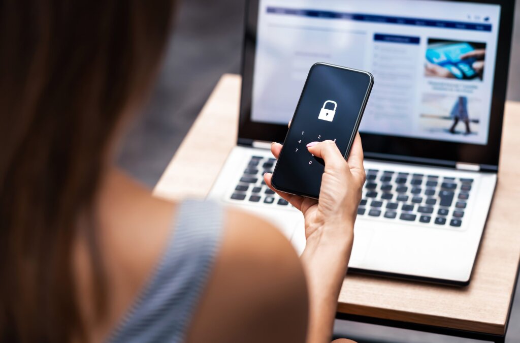 Woman holding a phone with a locked icon entering an unlock code.