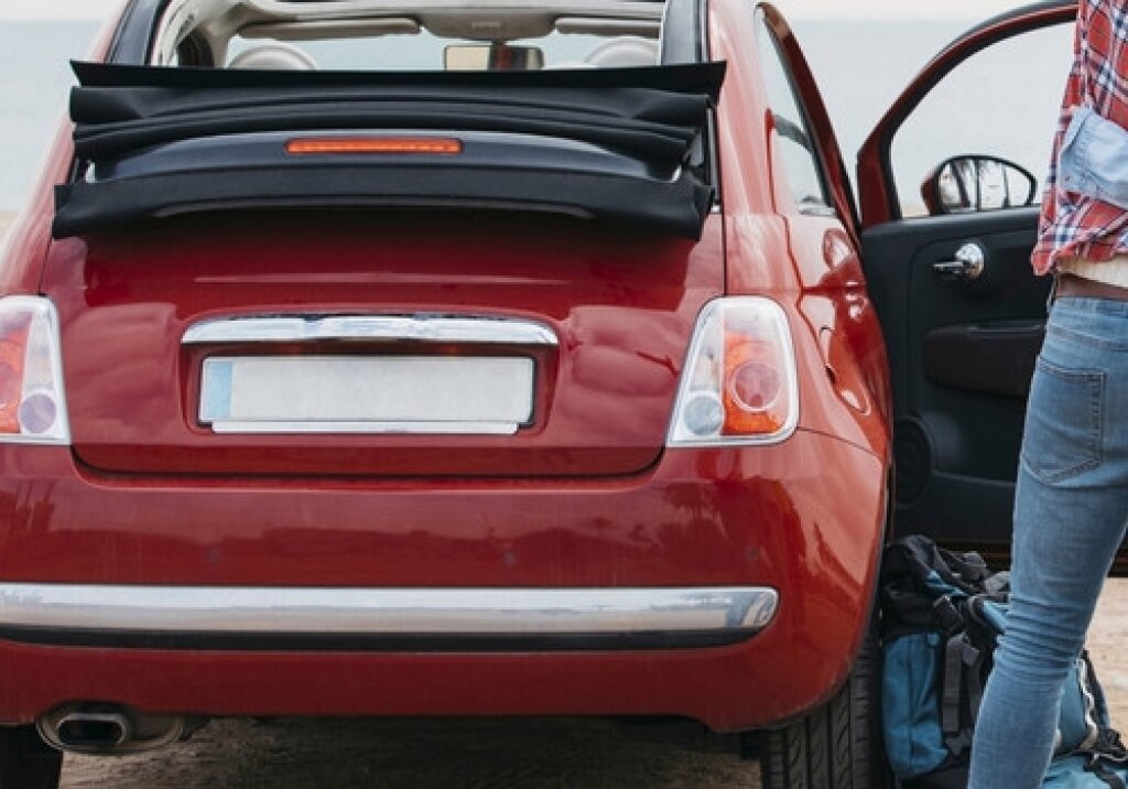 Rear of a red car with license plate blurred out.