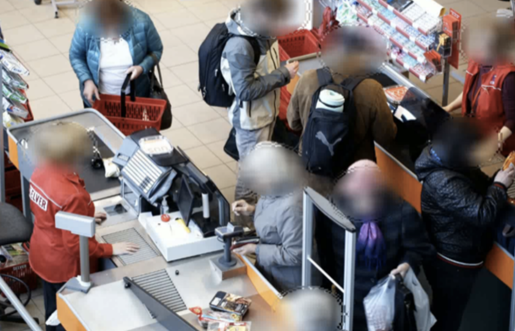 An image of people at a till in a store with blurred faces.